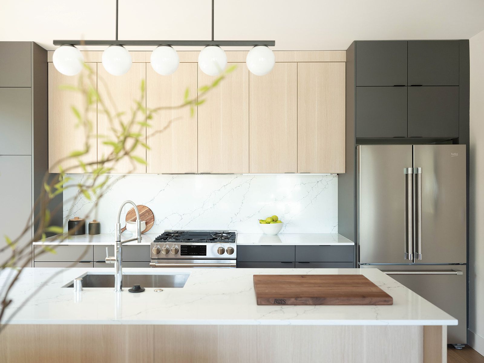 Kitchen with light oak cabinets, quartz island and globe pendant lights in a Bungalow Building home