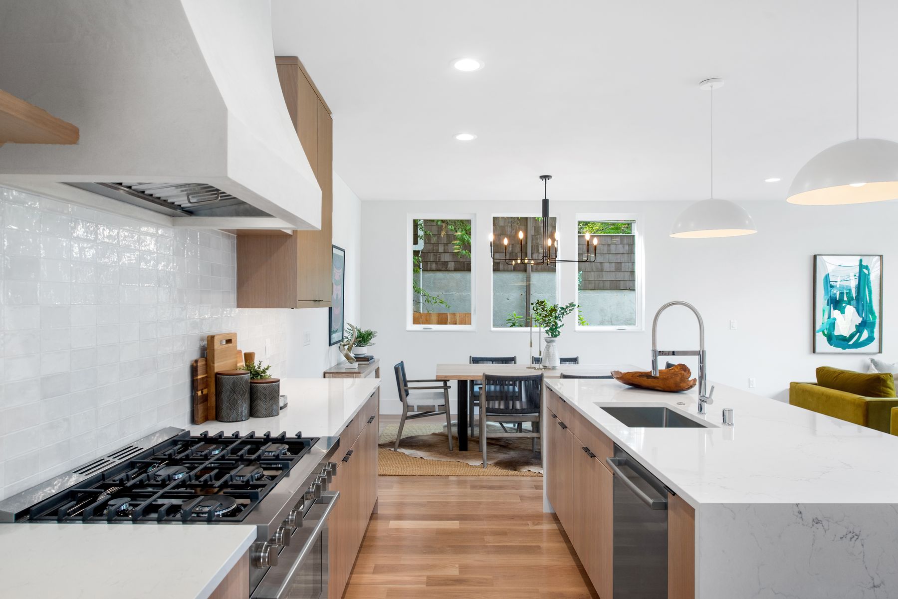 Bright kitchen with white tile, wood shelving and a gas range
